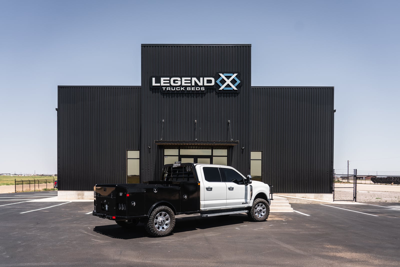 White pickup with a black Legend X Apollo service body parked at Legend X headquarters.
