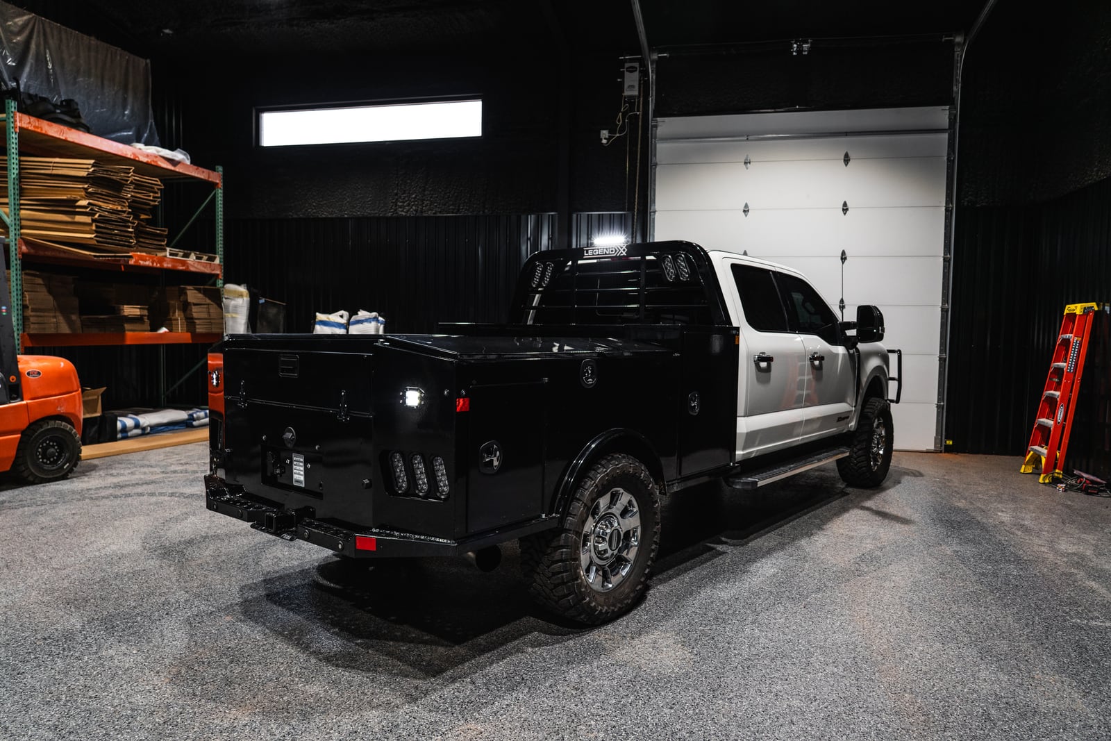 Rear three-quarter indoor view of a black Apollo service body with work lights illuminated.