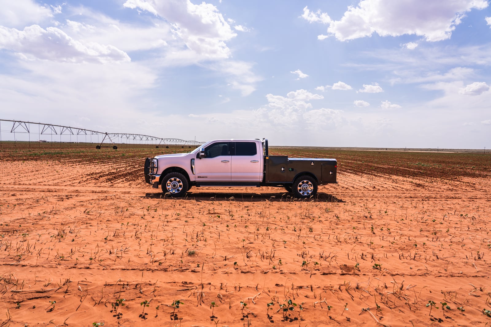 Wide Apollo work-truck profile with open sky and an irrigation pivot behind it.
