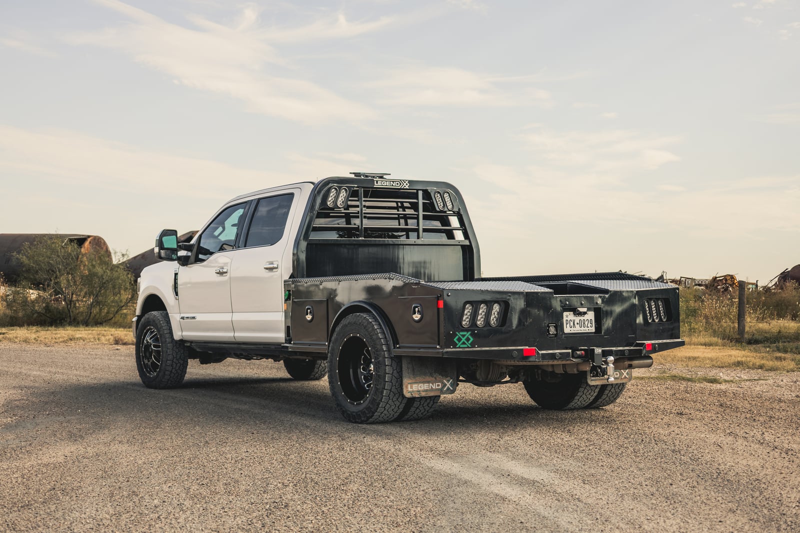 Black Legend X Phoenix flatbed on a white pickup viewed from the rear on a rural road.