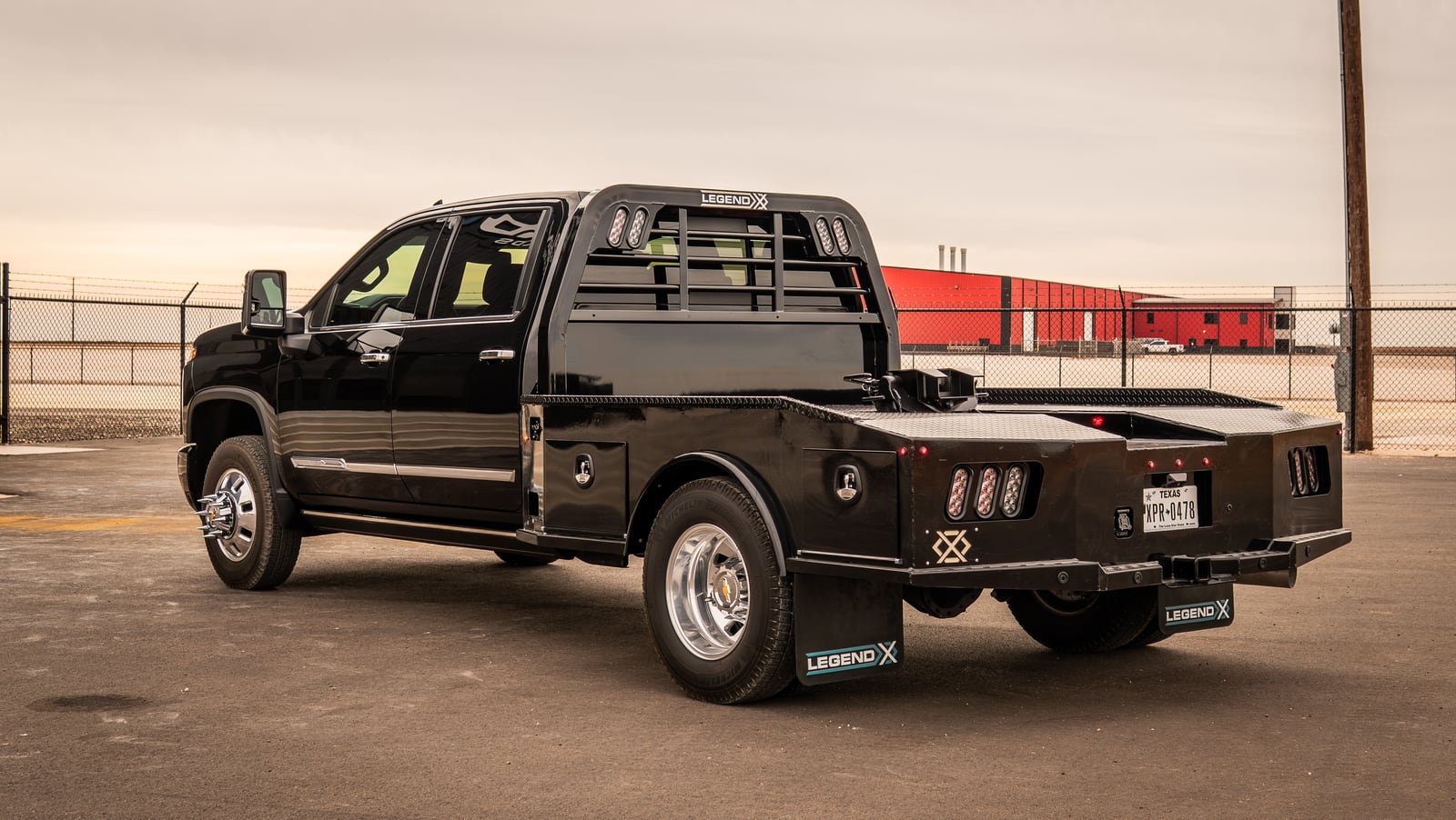 White pickup with a black Legend X Phoenix flatbed shown from the side on a rural road.