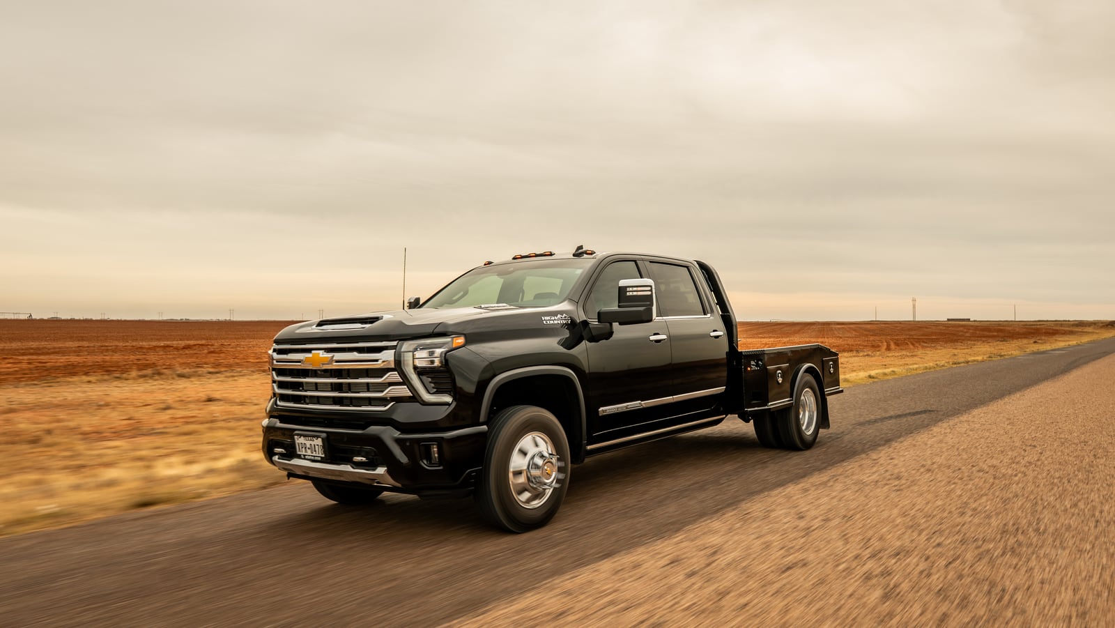White pickup with a black Legend X Phoenix flatbed traveling on a rural road.