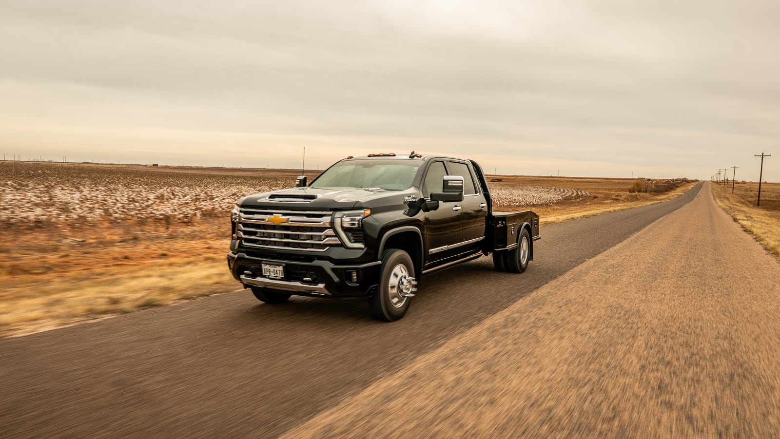 Black Chevrolet work truck and black Phoenix bed traveling through open country.
