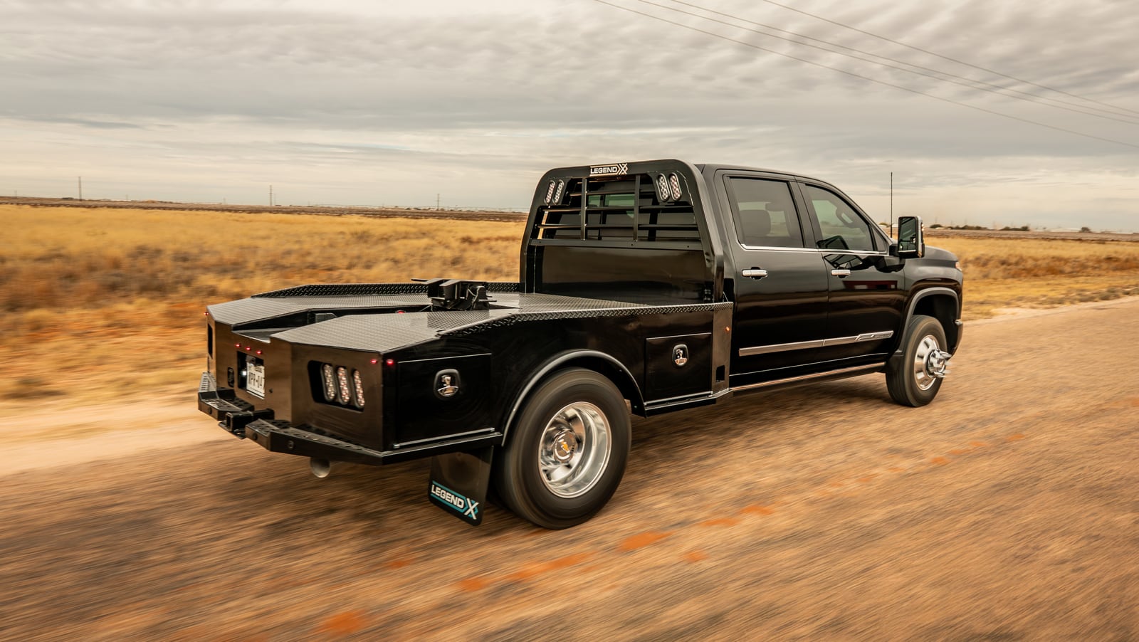 Rolling rear three-quarter view of a black Chevrolet truck with a black Phoenix bed.