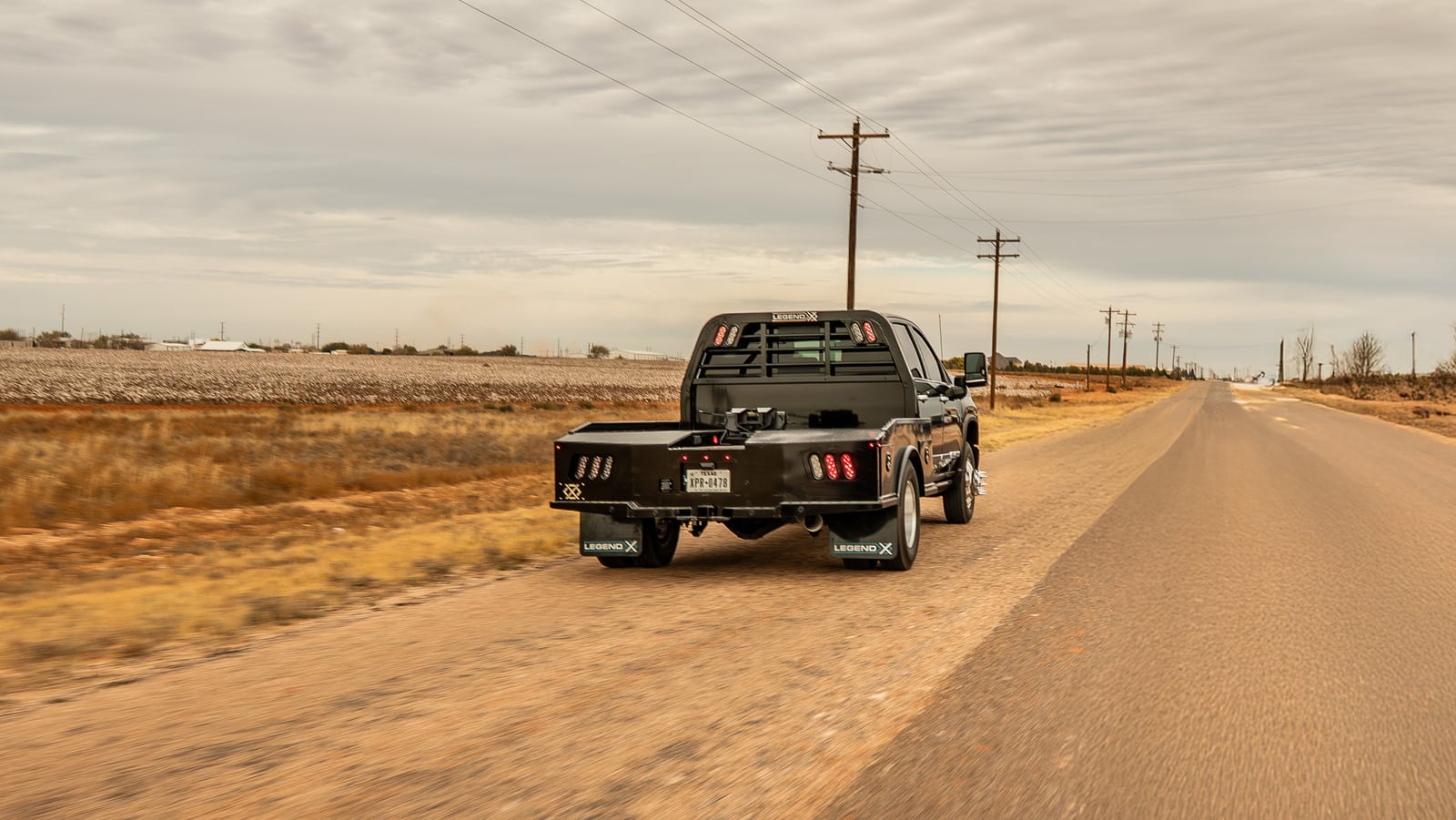 Black Phoenix-equipped Chevrolet dually moving along a rural road.