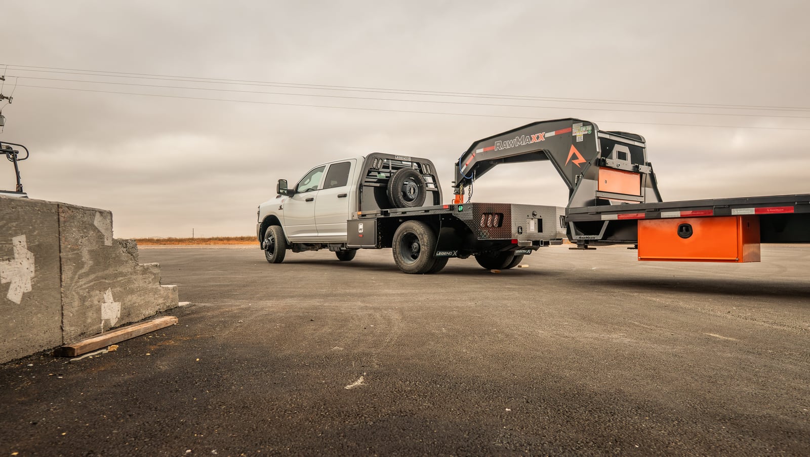Black Legend X Spartan flatbed on a white pickup towing a gooseneck trailer.