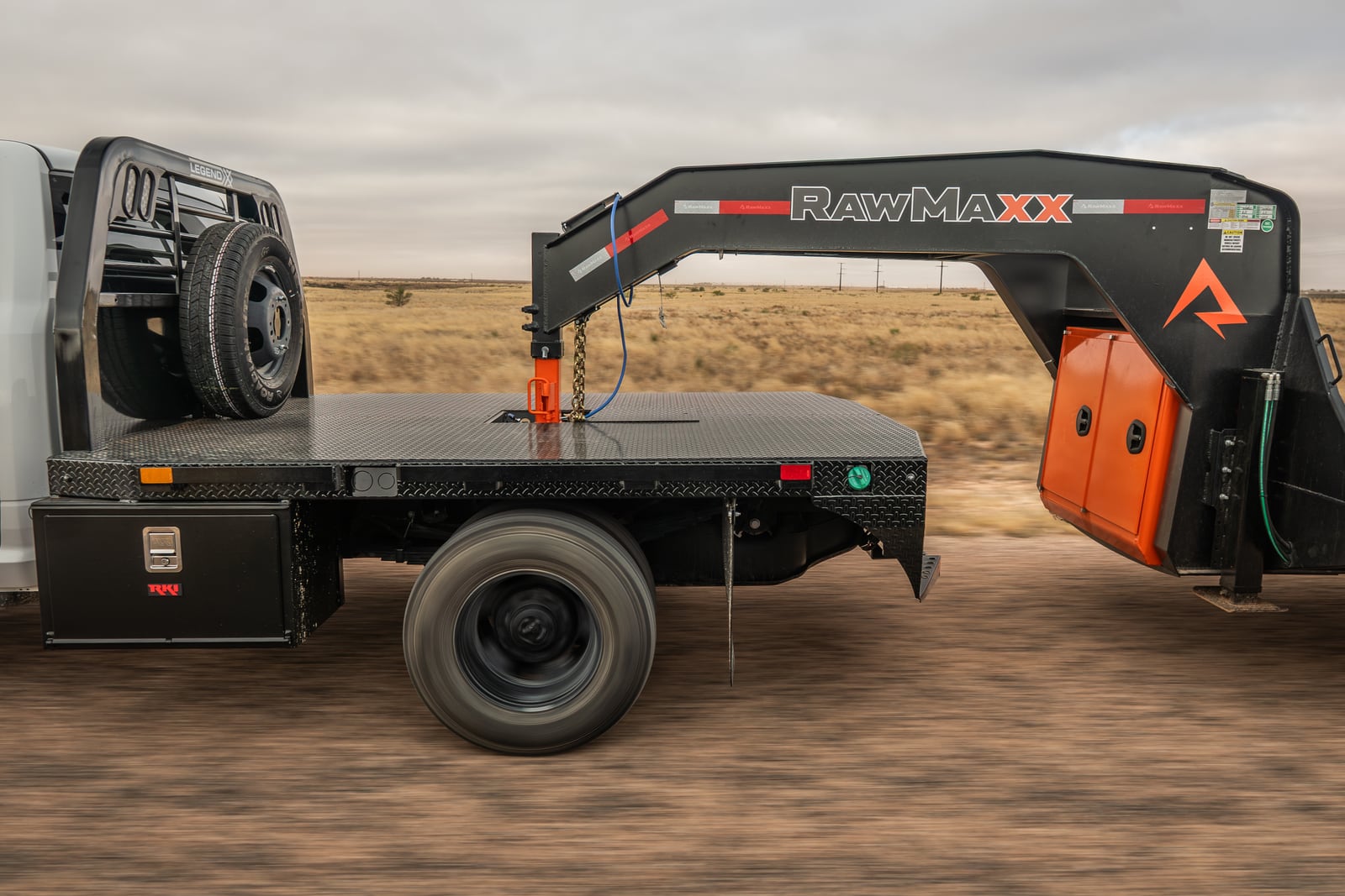 Side view of a black Legend X Spartan flatbed on a white pickup.