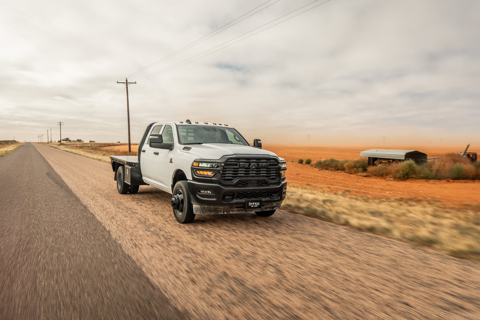White pickup with a black Legend X Spartan flatbed driving on a rural road.