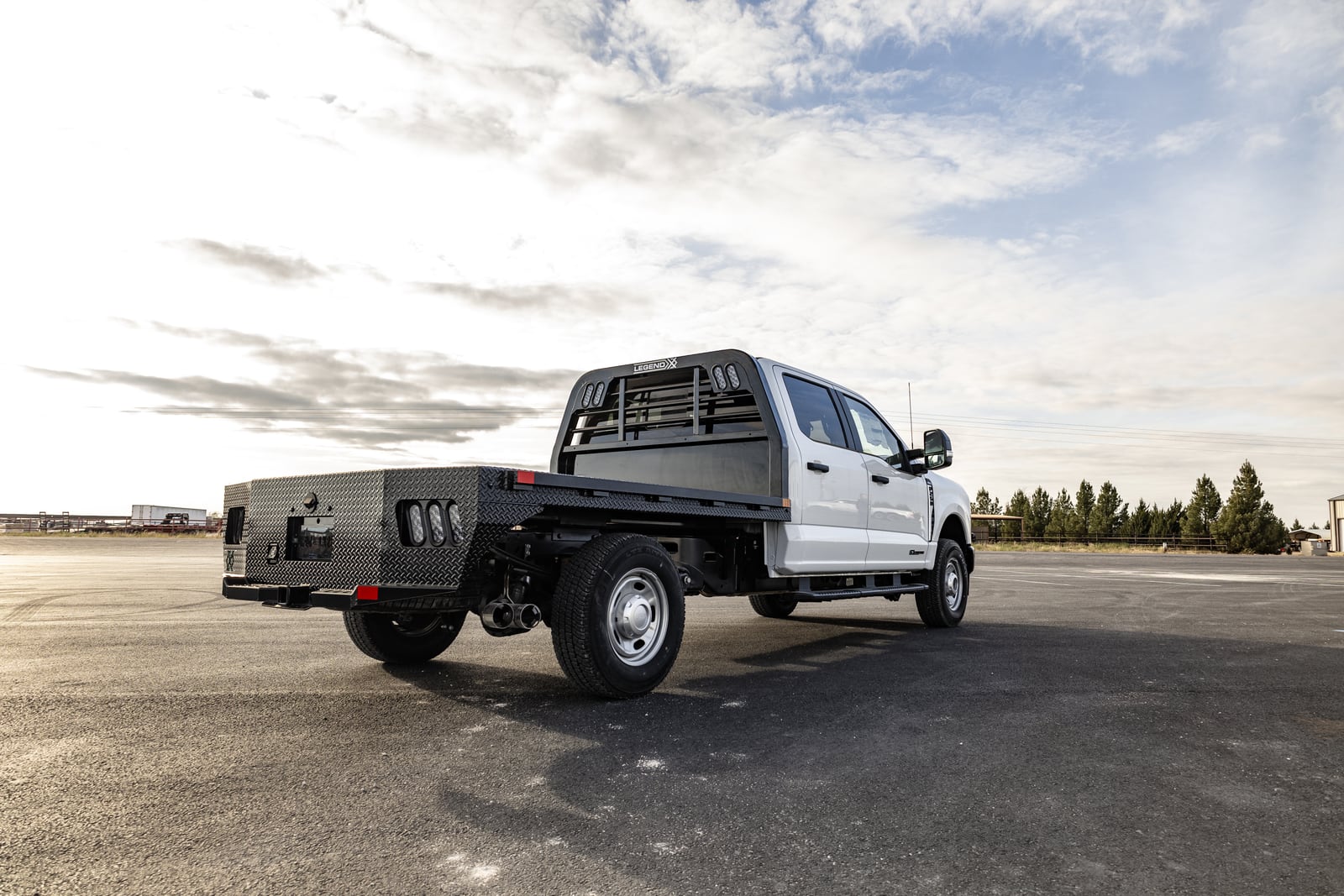 White Ford pickup with a black Legend X Spartan flatbed viewed from the rear.