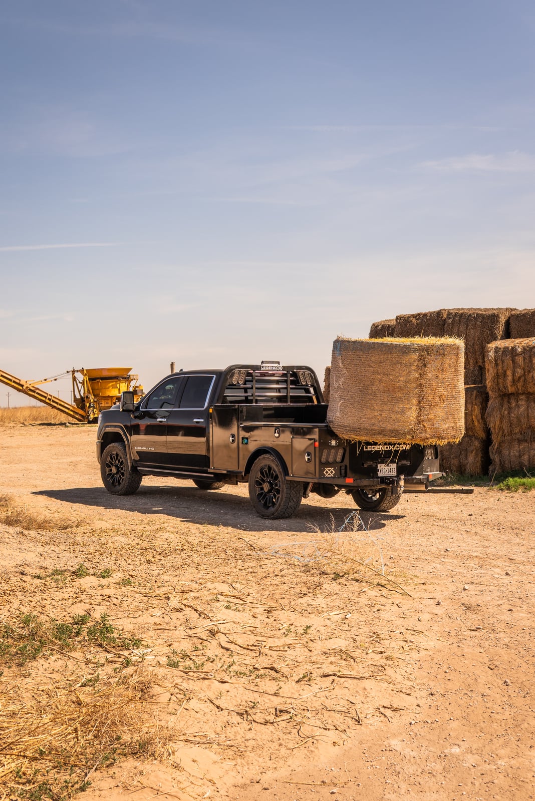 Wide ranch view of a Legend X spike bed carrying a round hay bale.