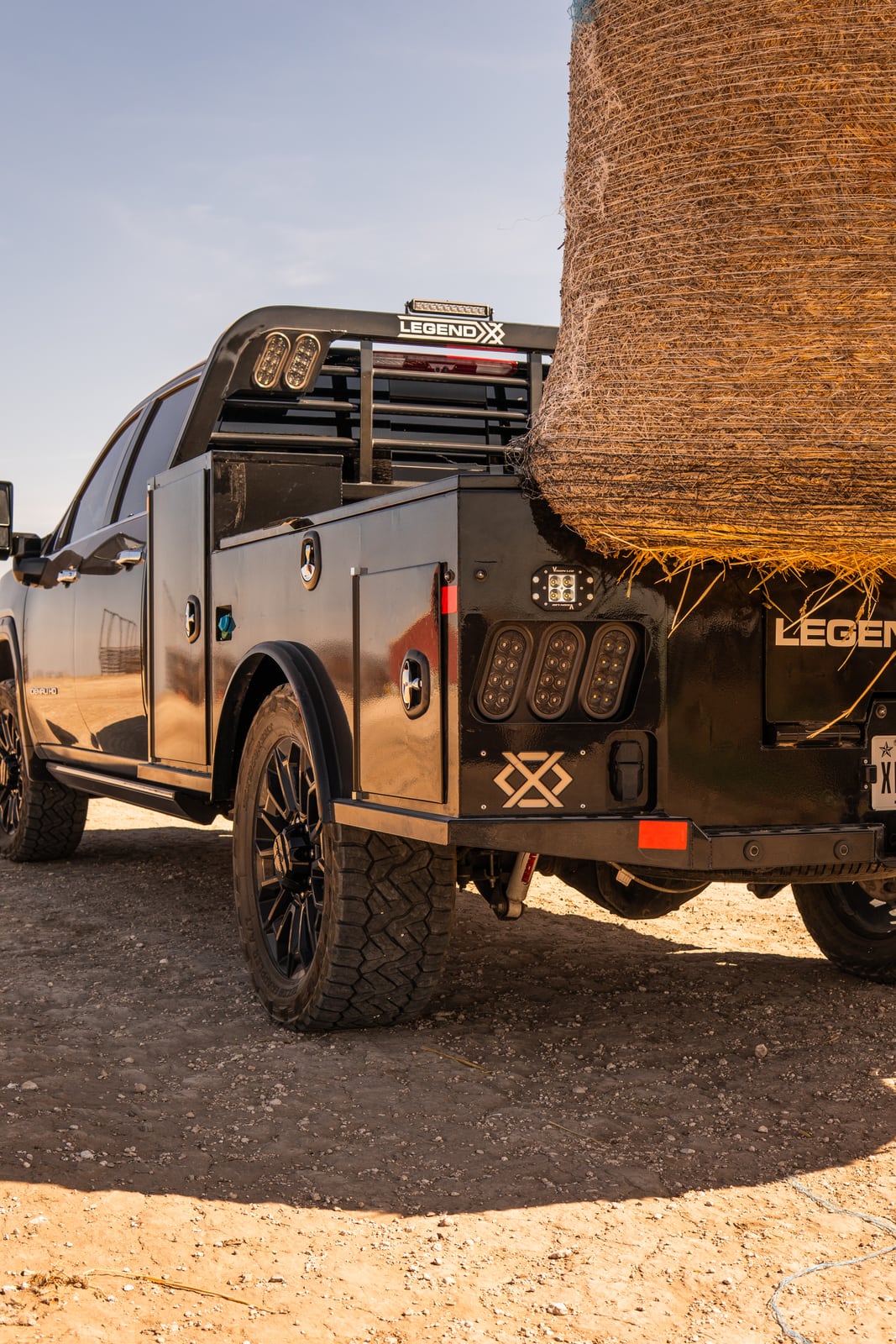 Portrait rear view of a Legend X spike bed loaded with a round hay bale.