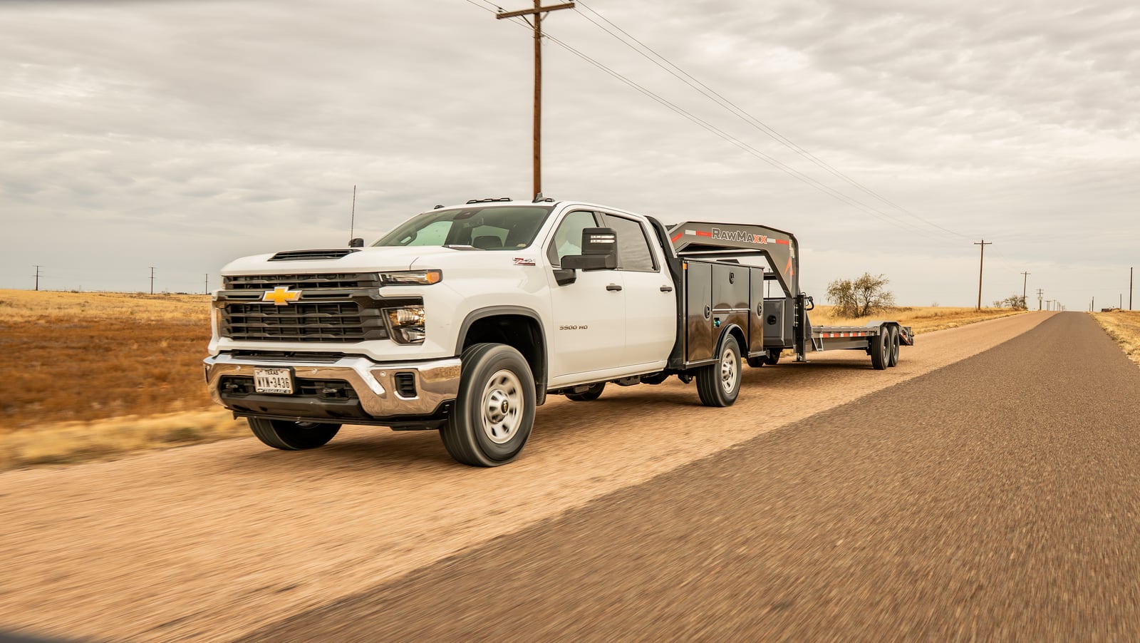 White pickup with a black Legend X Titan service body towing a gooseneck trailer on a rural road.