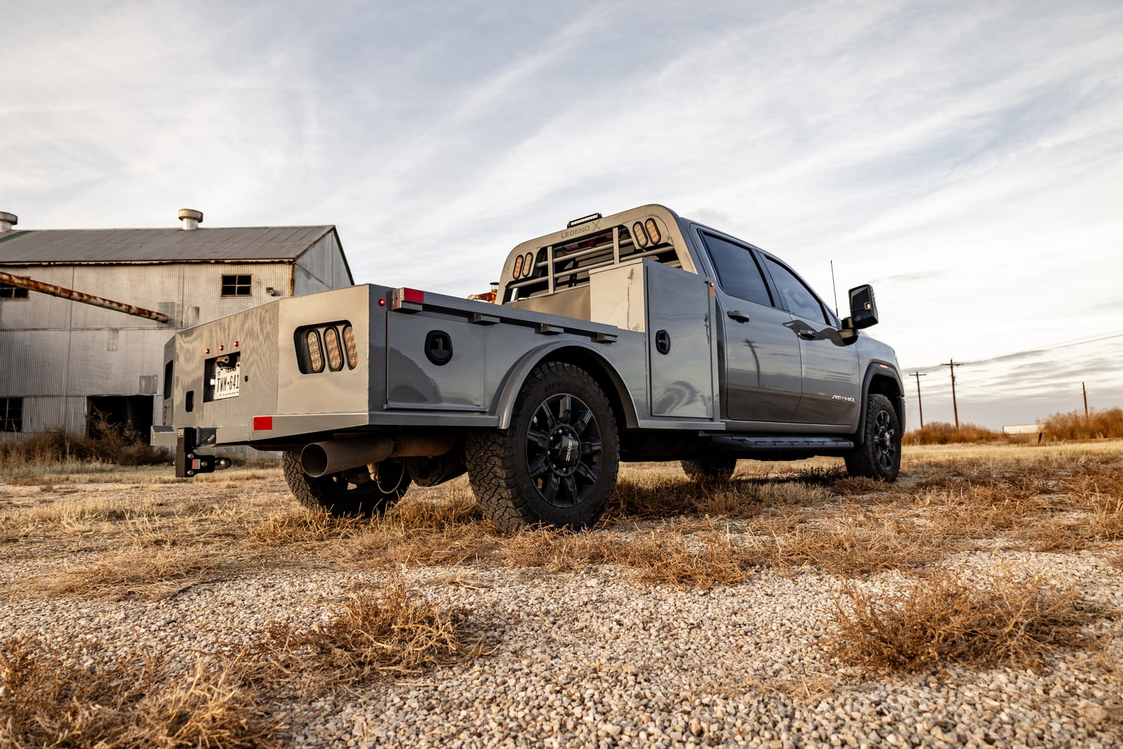 Gray pickup with a gray Legend X Viking Pro service body viewed from the rear beside a farm building.