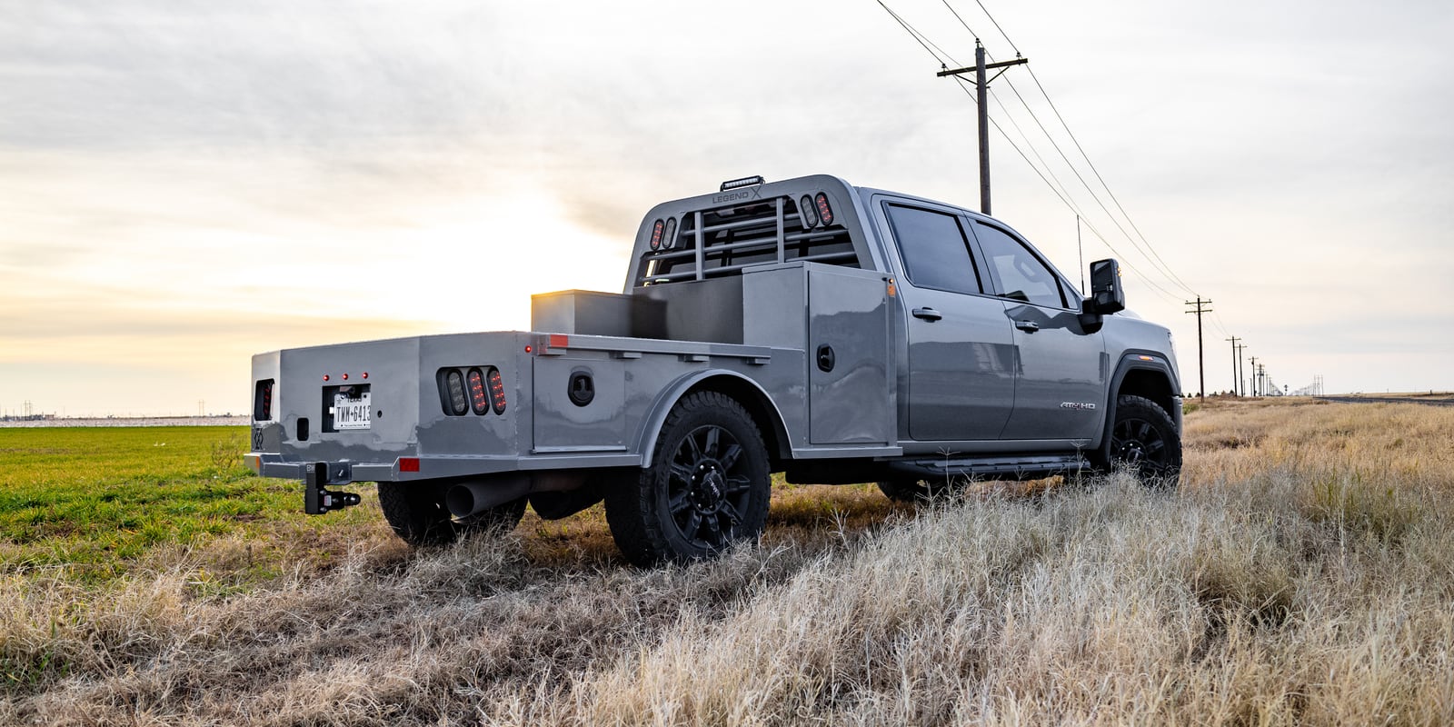 Gray pickup with a gray Legend X Viking Pro service body parked beside a field at sunset.