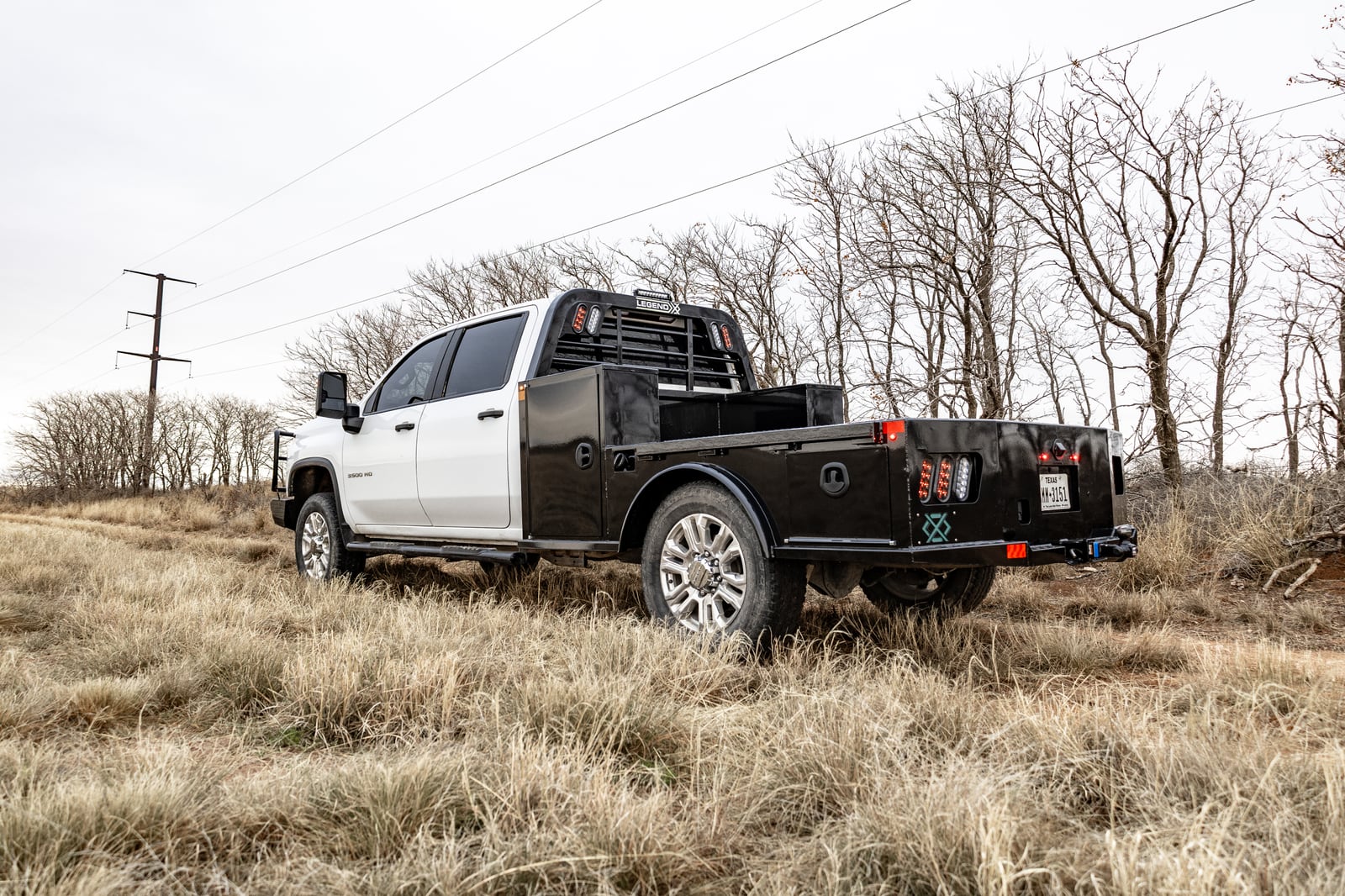 Black Legend X Viking Pro bed on a white pickup in a grassy field.