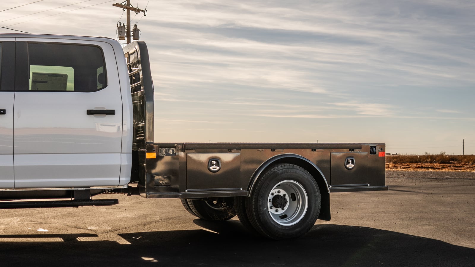 Full side view of a black Legend X Viking flatbed on a white pickup.