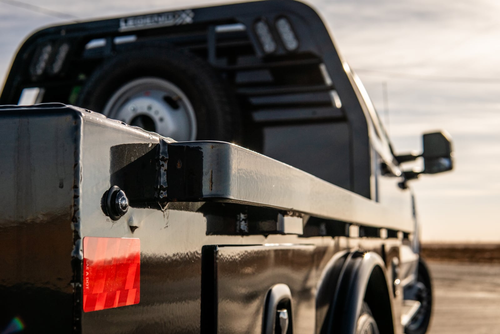 Side rails and stake pockets along the deck of a black Legend X Viking bed.