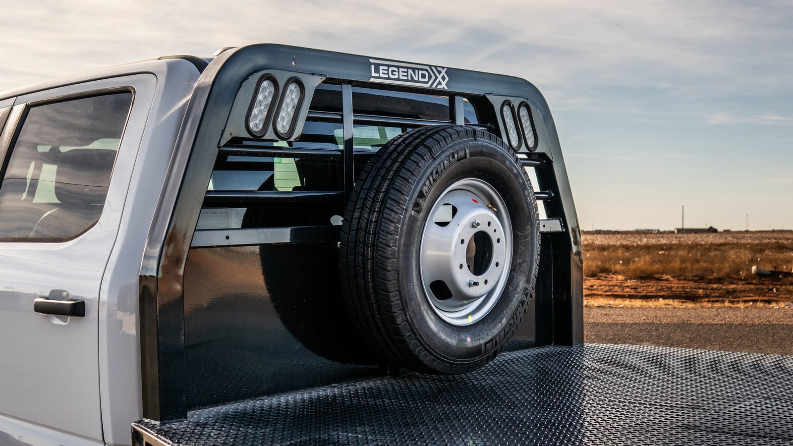 Spare tire mounted on the headache rack above the black Legend X Viking flatbed deck.