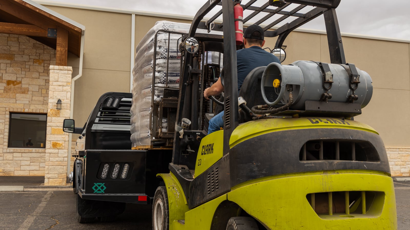 Forklift operator loading a pallet onto a Legend X Viking flatbed.